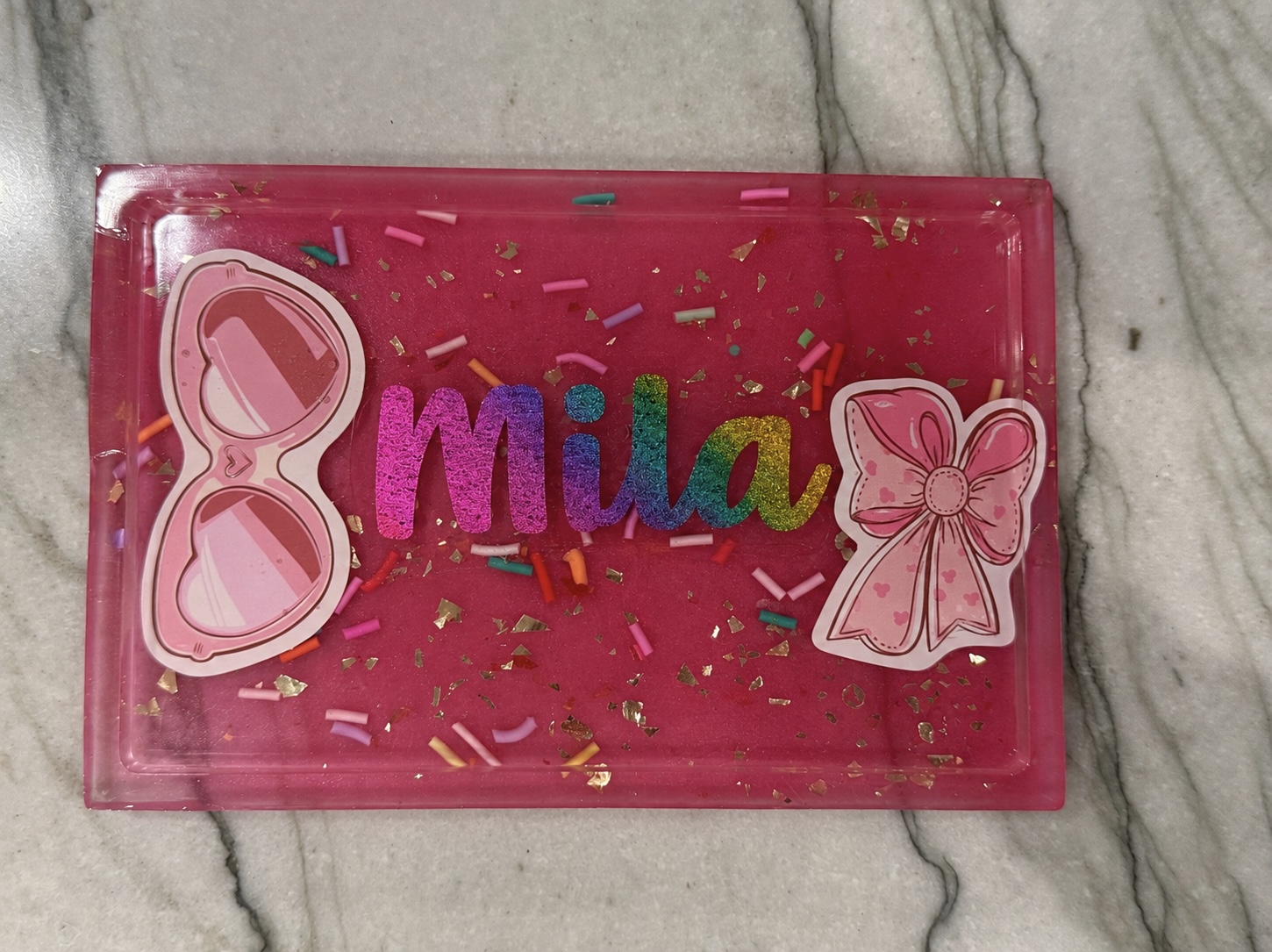 Pink resin trinket tray personalized with the name Mila, sunglasses and bow accents